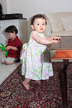 A baby girl stands near a table